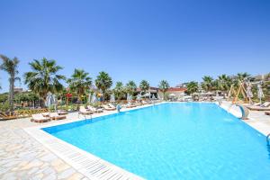 a large swimming pool with lounge chairs and palm trees at Hotel Lake Park Ksamil in Ksamil