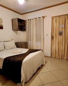 a bedroom with a bed and a wooden door at Pousada Belezinha in Arraial do Cabo