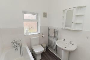 a white bathroom with a toilet and a sink at Woodington House in Birmingham