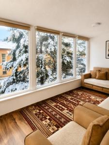 a living room with two couches and two large windows at Eloi Apartment in Gjakove