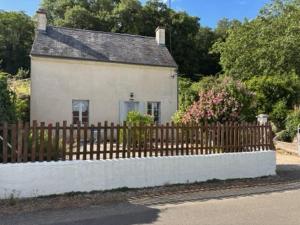 a small white house with a wooden fence at Gîte les Huttières in Cravant-les-Coteaux