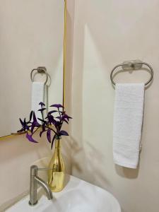 a bathroom sink with a vase with purple flowers in it at Casa Bambú Hotel in Masaya