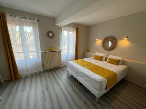 a bedroom with a large bed and two windows at Hotel Chiffre in Albi