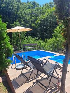 a pair of chairs and an umbrella next to a swimming pool at Forest Oasis Slatina in Slatina Varoš