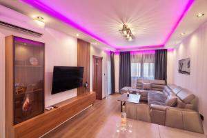 a living room with a couch and a tv with purple lights at Villa President 2 in Kunjići