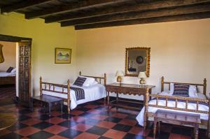 a bedroom with two beds and a table and a mirror at Hotel Museo Mayan Inn in Chichicastenango