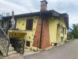 a yellow house with a brick chimney and a balcony at Casa Helvezia in Cadenazzo