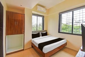 a bedroom with a bed and two windows at Hotel O RVC GRAND CENTRAL in Viman Nagar