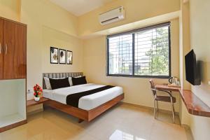 a bedroom with a bed and a desk and a window at Hotel O RVC GRAND CENTRAL in Viman Nagar