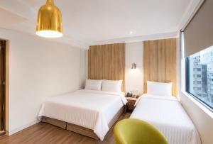 two beds in a hotel room with a green chair at Hotel Relax II in Taipei +42 photos