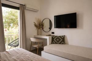 a bedroom with a bed and a tv and a window at Abelia Boutique Rooms in Tsilivi