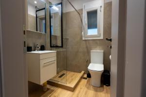 ein Badezimmer mit Toilette, Waschbecken und Spiegel in der Unterkunft ERA Suites in Stomio + 64 Fotos