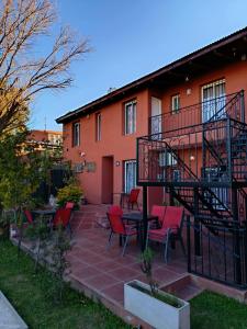 a patio with red chairs and a table in front of a building at La caballeriza departamentos in Alta Gracia