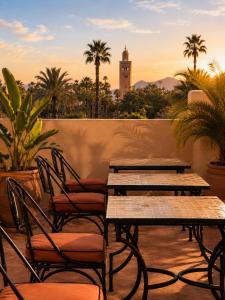 a group of tables and chairs on a balcony with a clock tower at Riad Sesame in Marrakesh