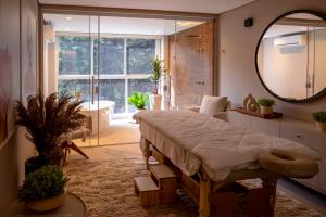 a bedroom with a large bed and a mirror at Champet Boutique Hotel in Campos do Jordão