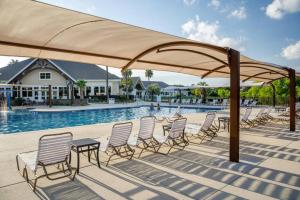 a group of chairs under a large umbrella next to a pool at 1315 Pelican Watch Villas-Beachfront & Amenities - on Sale in Seabrook Island