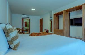 a bedroom with a large white bed with a television at Cairé Suites in Itacaré