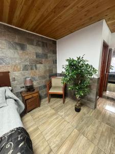 a bedroom with a stone wall with a bed and a chair at Hospedaje Shuyen in Victoria