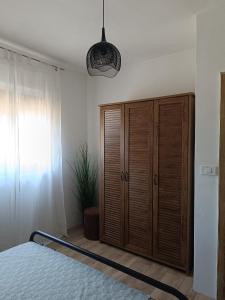 a bedroom with a wooden cabinet and a bed at Apartment Hidden Garden in Pula