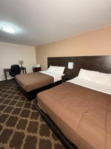a hotel room with two beds and a chair at Falls Lodge by the Falls (Formerly Knights Inn) in Niagara Falls +37 photos