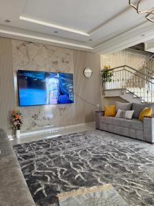 a living room with a couch and a tv on a wall at Comfort House in Azib Aïn el Alak