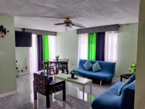 a living room with blue furniture and green curtains at Beach-side condos at Turtle Beach Towers in Ocho Rios
