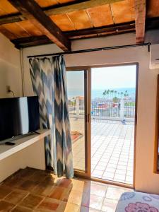a living room with a tv and a sliding glass door at Casa Rey Sol Vallarta in Puerto Vallarta