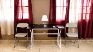 a desk with three chairs and a lamp in a room with red curtains at Suite Familiar Afrodita - Centro Histórico in Comayagua