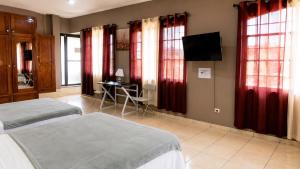 a bedroom with two beds and a television and windows at Suite Familiar Afrodita - Centro Histórico in Comayagua