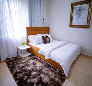 a bedroom with a bed with white sheets and a rug at Rosewood Cozy homes in Mbeya
