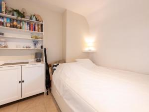 a bedroom with a white bed and a book shelf at Nieuwendamme 40C in Lombardsijde +10 photos