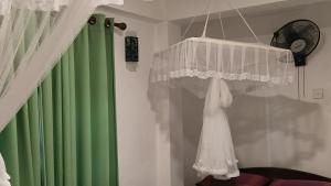 a white dress hanging from a window next to a green curtain at Green Woods Guest in Kandy +91 photos