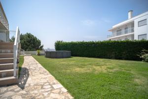 a backyard with a grassy yard next to a building at Feel Nazaré - Ocean Villa in Nazaré