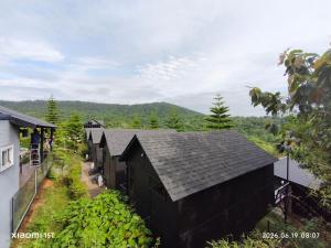 a row of black buildings with a mountain in the background at บ้านพัก เย็นเย็นแคมป์ปิ้ง อิน เขาค้อ in Ban Pa Daeng