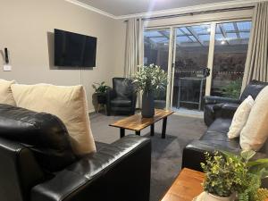a living room with black leather furniture and a tv at Bella Nicola in Bright