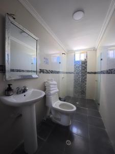 a bathroom with a sink and a toilet and a mirror at Apartamentos Isla Tropical in San Andrés