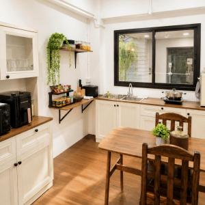 a kitchen with white cabinets and a wooden table at La Vie Résidence in Chiang Mai