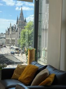 a couch in front of a window with a view of a building at Historic Centre Apartment - Ghent Belfry & St Nicholas Church View in Ghent +25 photos