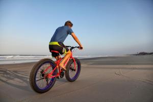 a man riding a bike on the beach at Travessia Beach Lodge in Inhambane