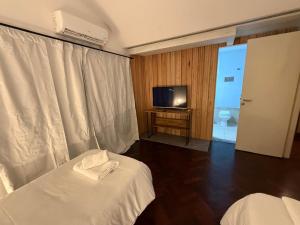 ein Hotelzimmer mit zwei Betten und einem Fernseher in der Unterkunft La Casona Apart & Suites in Ezeiza