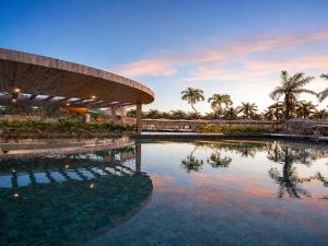 a pool at a resort with palm trees in the background at Beach Resort in Salinópolis