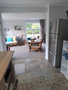 a kitchen with a refrigerator and a living room at Among The Tuii in Katikati