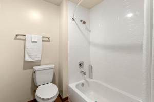 a white bathroom with a toilet and a bath tub at Good Nite Inn Fremont in Fremont +5 photos