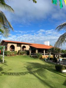 a building with a green yard and palm trees at Pousada Sol Nascente in Beberibe