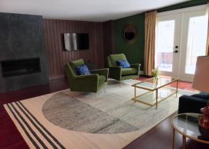 a living room with green chairs and a rug at Shelburne Springs Hotel in Shelburne Falls
