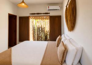 a bedroom with a white bed and a window at Lá na Chay Caraíva Refúgio tranquilo & experiência local in Caraíva