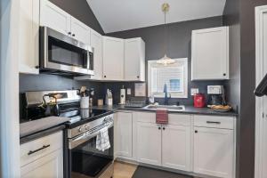 a kitchen with white cabinets and a stove top oven at Coral Cottage - Tiny Home at Hampton Beach in Hampton