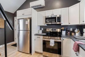 a kitchen with white cabinets and a stainless steel refrigerator at Coral Cottage - Tiny Home at Hampton Beach in Hampton