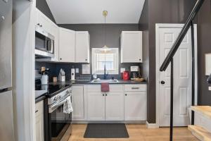 a kitchen with white cabinets and a sink at Coral Cottage - Tiny Home at Hampton Beach in Hampton