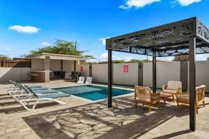 a pergola over a swimming pool with chairs and a patio at Monserat 33Q in Palm-Eagle Beach